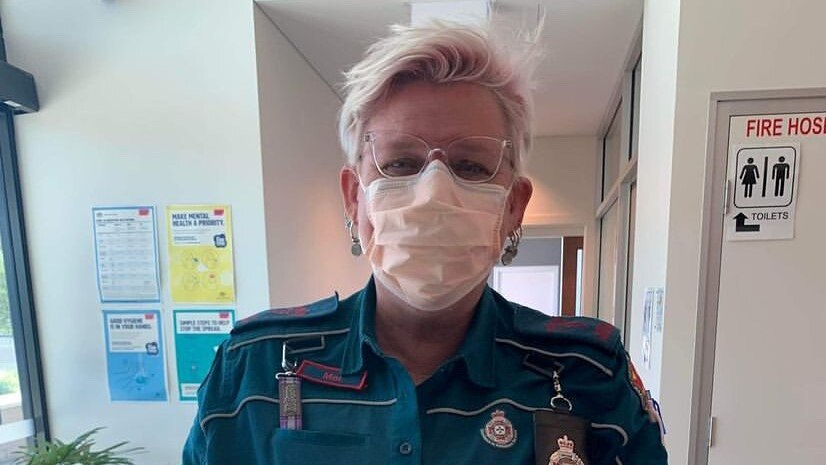 Paramedic with short, light pink hair and classes wearing face mask 