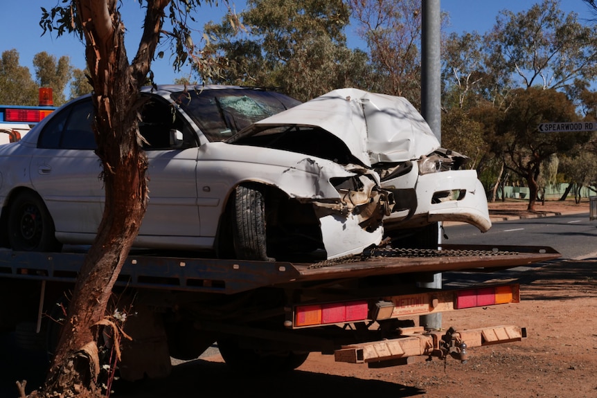 A white car with a smashed bonnet on a tow truck