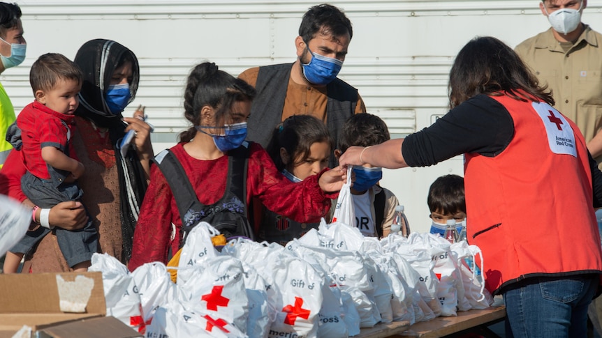 Person in a red cross vest hands out supplies