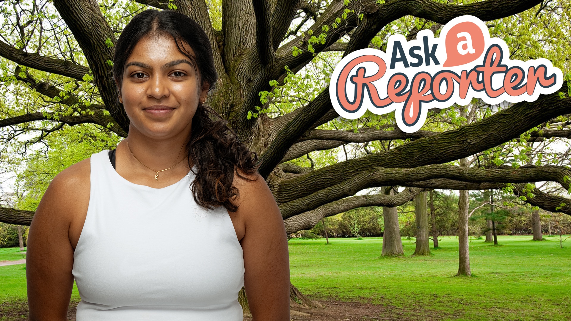Kushi smiles to camera. Big tree with expansive branches behind her.