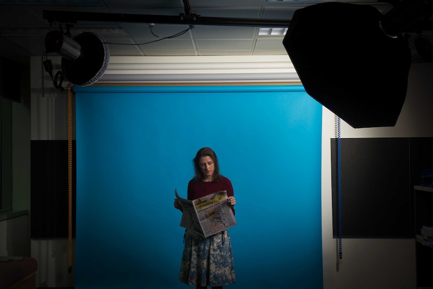 Saffron Howden holds a copy of Crinkling News in front of a blue screen