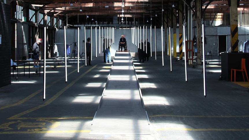 A warehouse with vertical hanging florescent lights in rows.