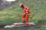 SES worker in Launceston sandbags nearly a swelling river.