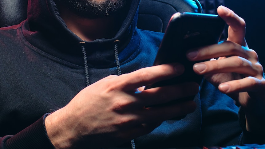 A close up of a man wearing black holding a phone.