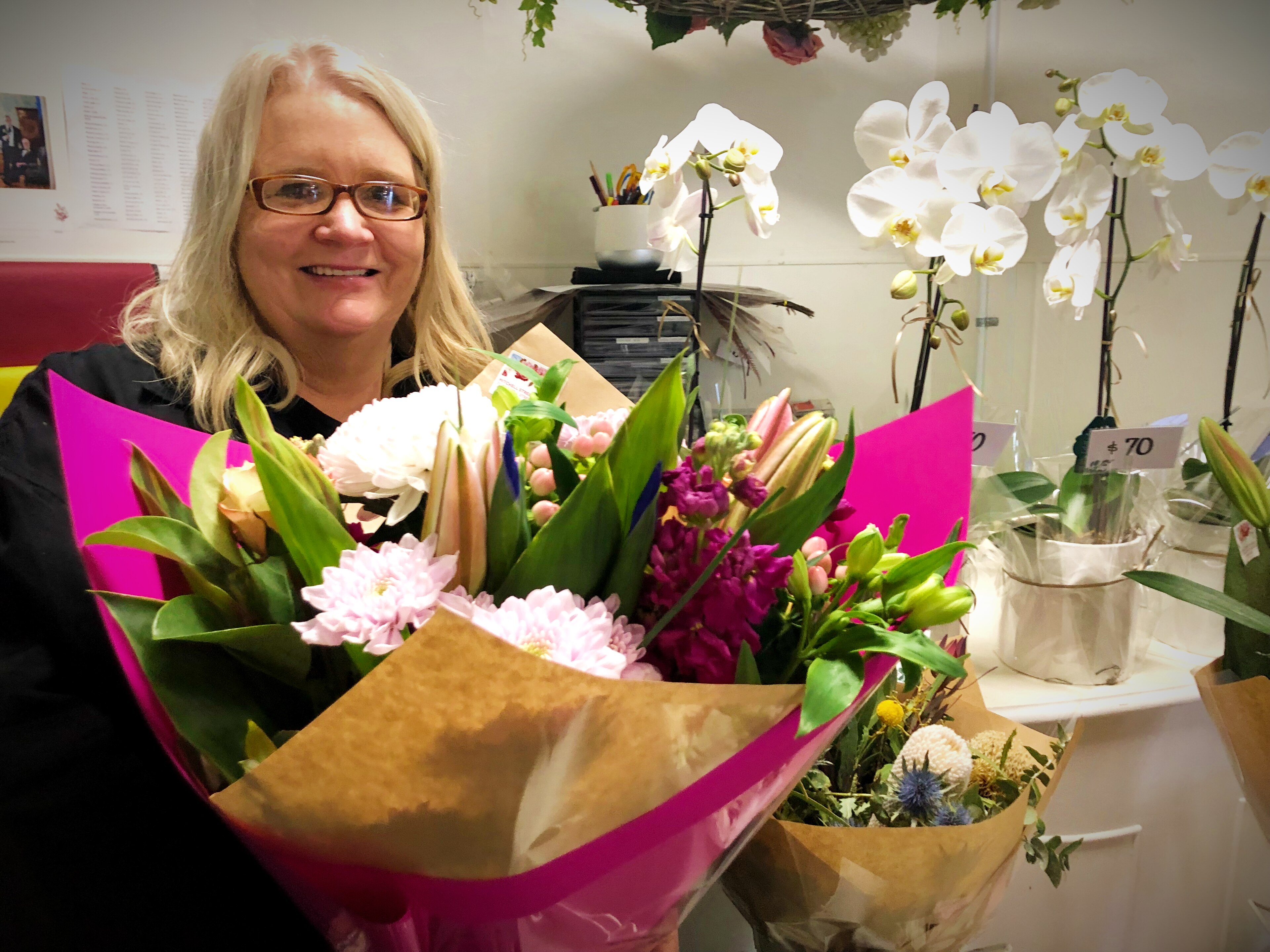 a blonde haired lady holds a bouquet of bright flowers