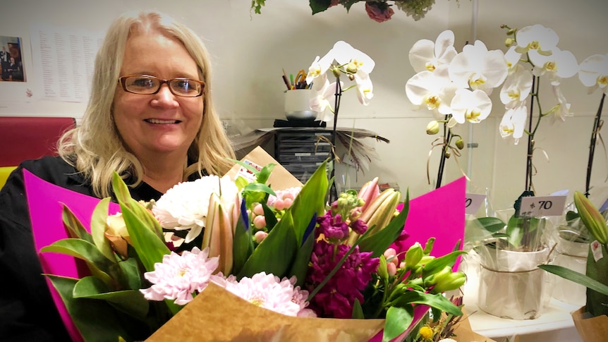 a blonde haired lady holds a bouquet of bright flowers