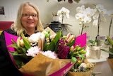 a blonde haired lady holds a bouquet of bright flowers