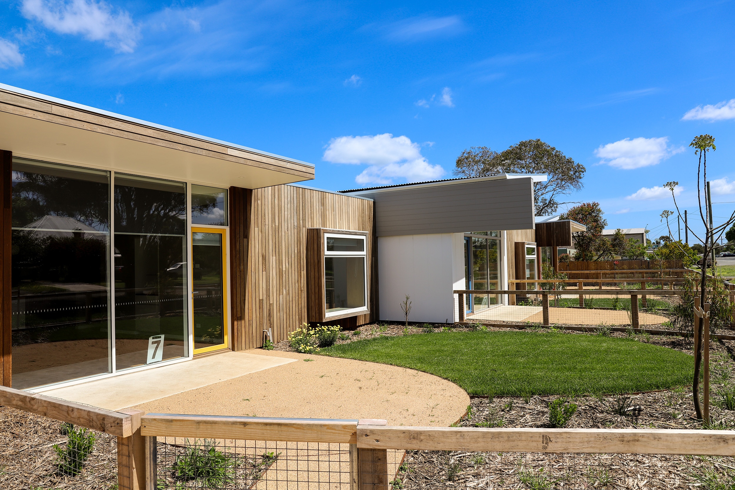 A line of architectually designed units with a mix of wood and concrete finishes line a quiet regional street