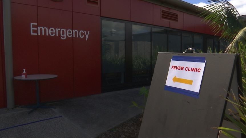 A sign reading 'Fever Clinic' with an arrow pointing to a red building with 'Emergency' on the side