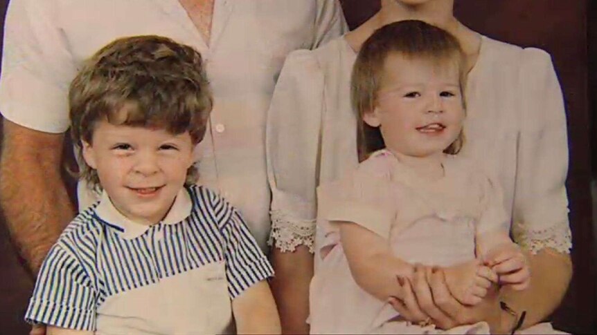 A zoomed-in photo shows the smiling faces of two children. Kyle wears a shirt with blue and white stripes, Latisha a pink dress