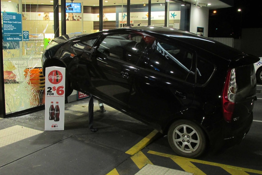 A black car crashed into the glass doors of a service station