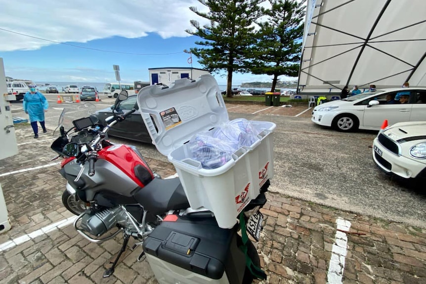 A box on the back of a motorcycle full of COVID-19 tests.