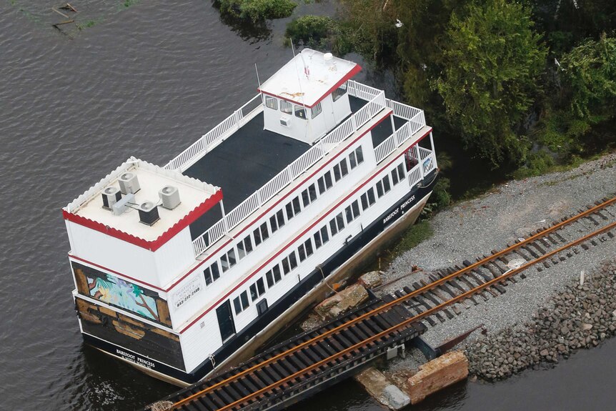 A tour boat is stacked up next to a railroad bridge