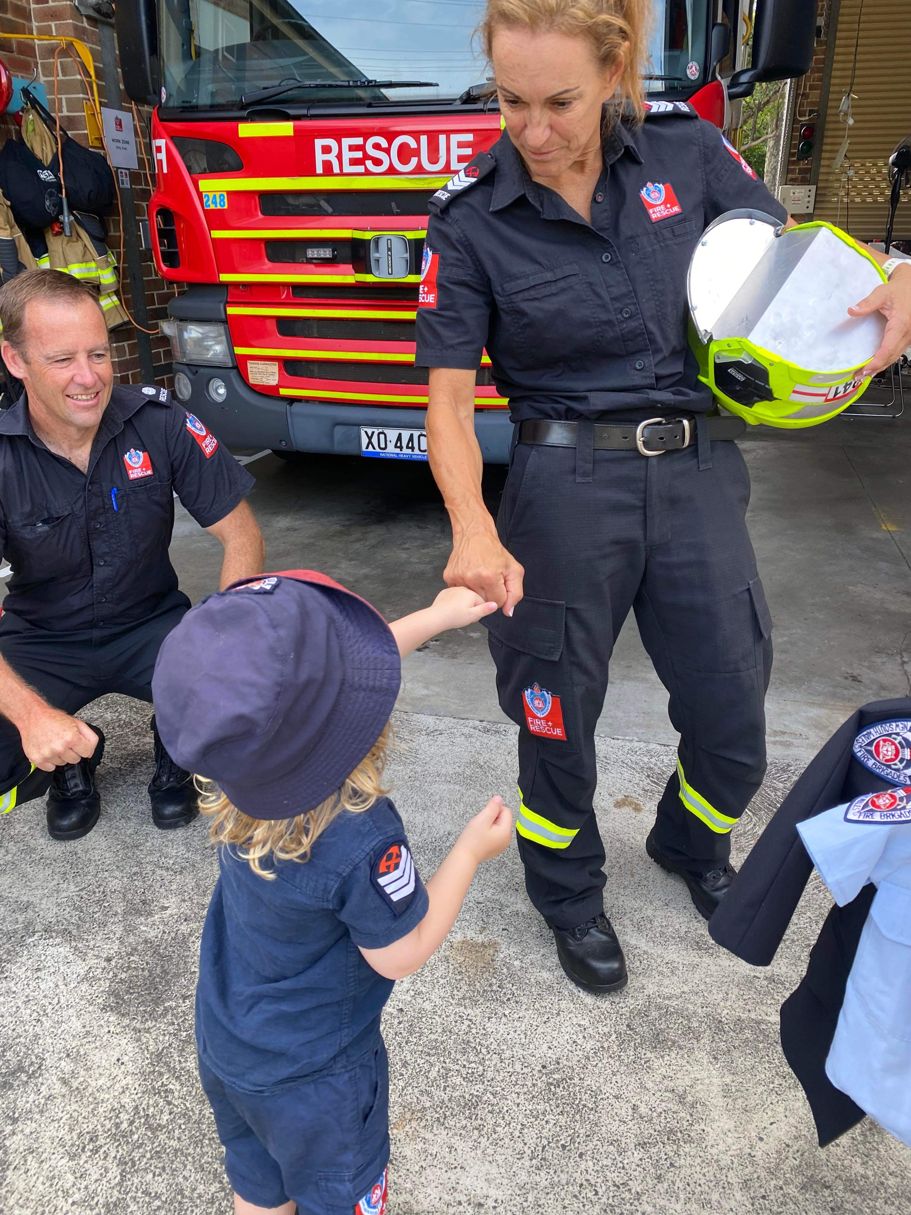 Blonde haired 4-year-old giving female firefighter a fist pump