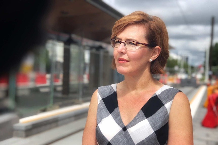Meegan Fitzharris stares out of frame at a light rail station.