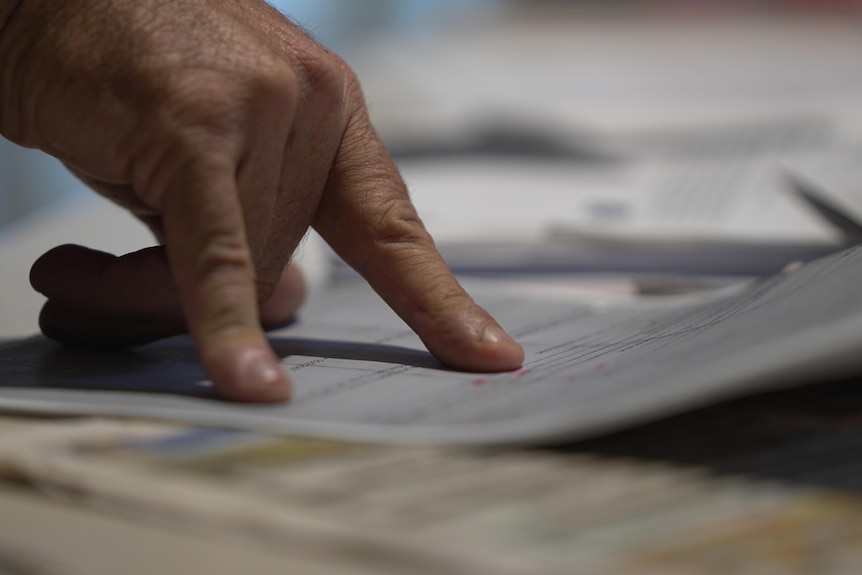 A man's hand points to a sentence on a page of a document 