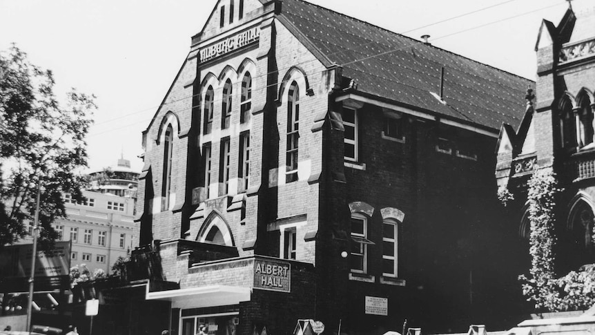 A large brick hall next to a church in 1967.