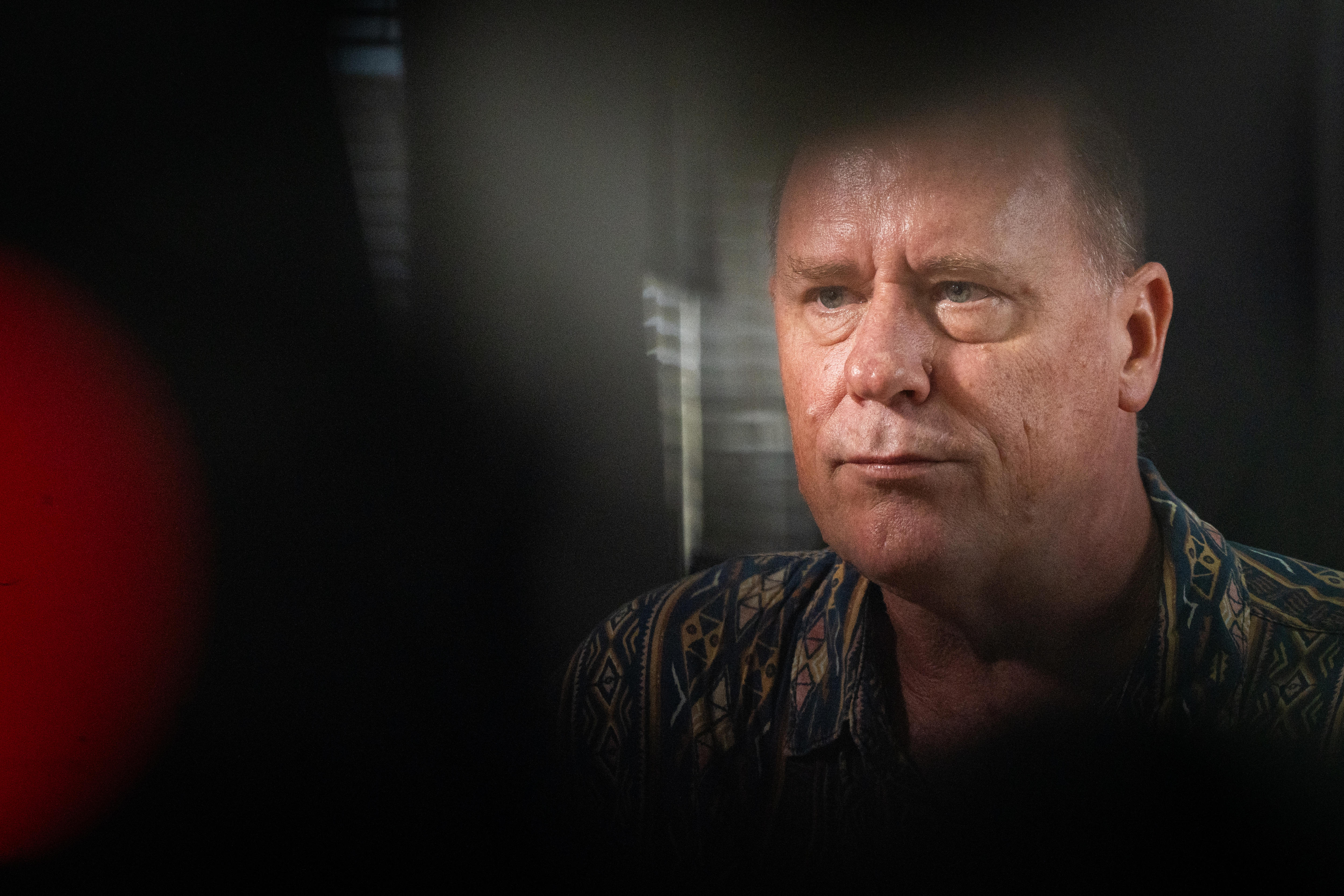 El rostro de un hombre está enmarcado por objetos en primer plano.