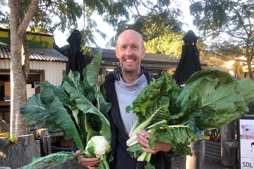 Neil Federer in front of his store holding vegetables.