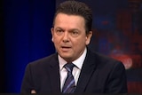 Nick Xenophon wears a dark suit and white tie, he has short dark hair.