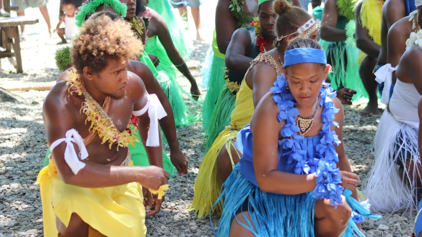 Freda Sikwae dancing with other villagers, and wearing traditional costumes, in the Solomon Islands.