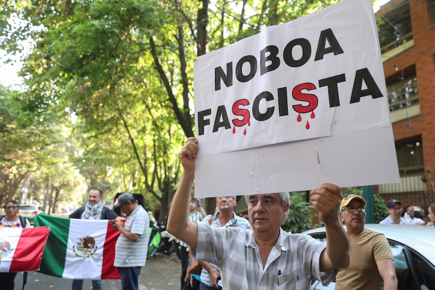 Man holds up sign reading 'Noboa Fascist' 