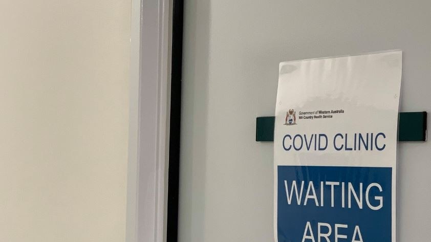 A sign on a door that says Covid Clinic waiting area