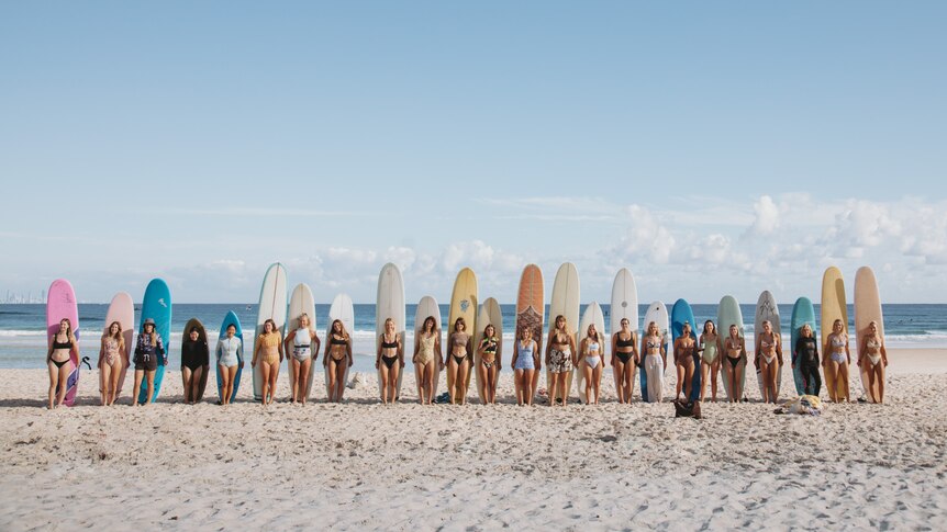 group of women with surf boards on the beach
