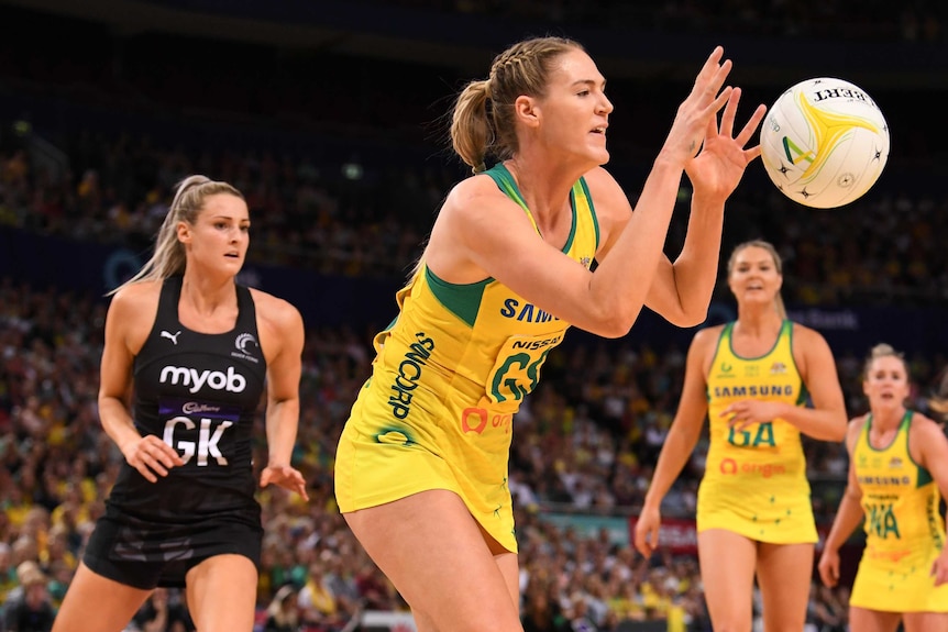 An Australian Diamonds netball player accepts a pass against New Zealand.