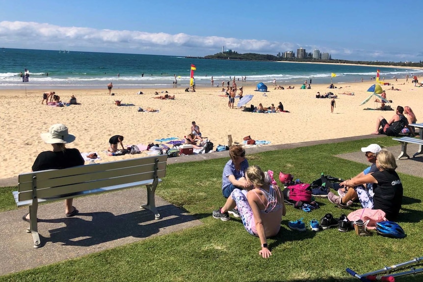 A beach dotted with people with blue skies.