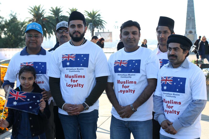 A group of Muslims in white shirts showing the Australian flag pose for a photo.