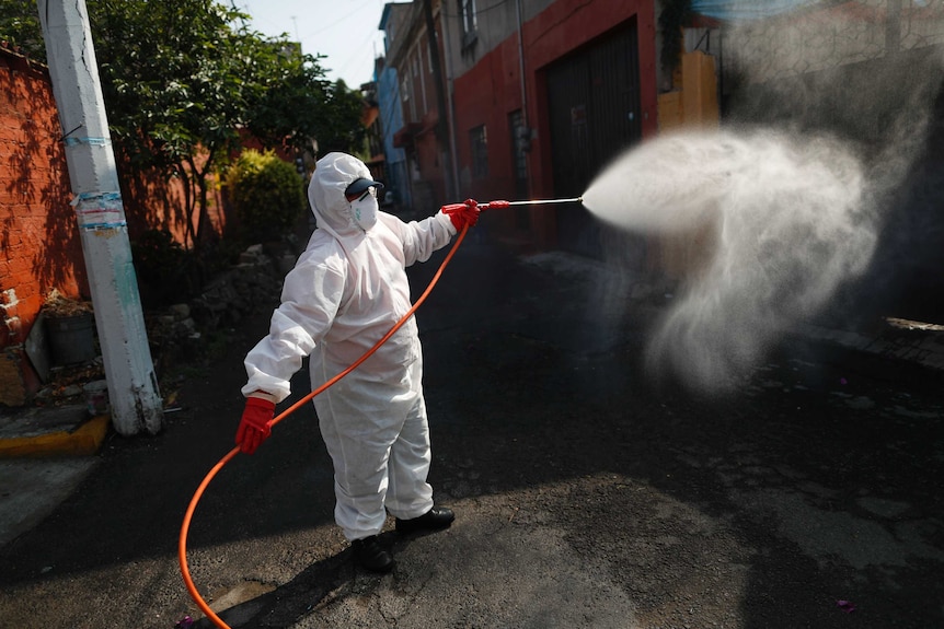 A public safety worker sprays a disinfectant solution in the streets of Mexico.