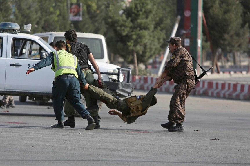 Afghan security personnel carry an injured officer after an attack