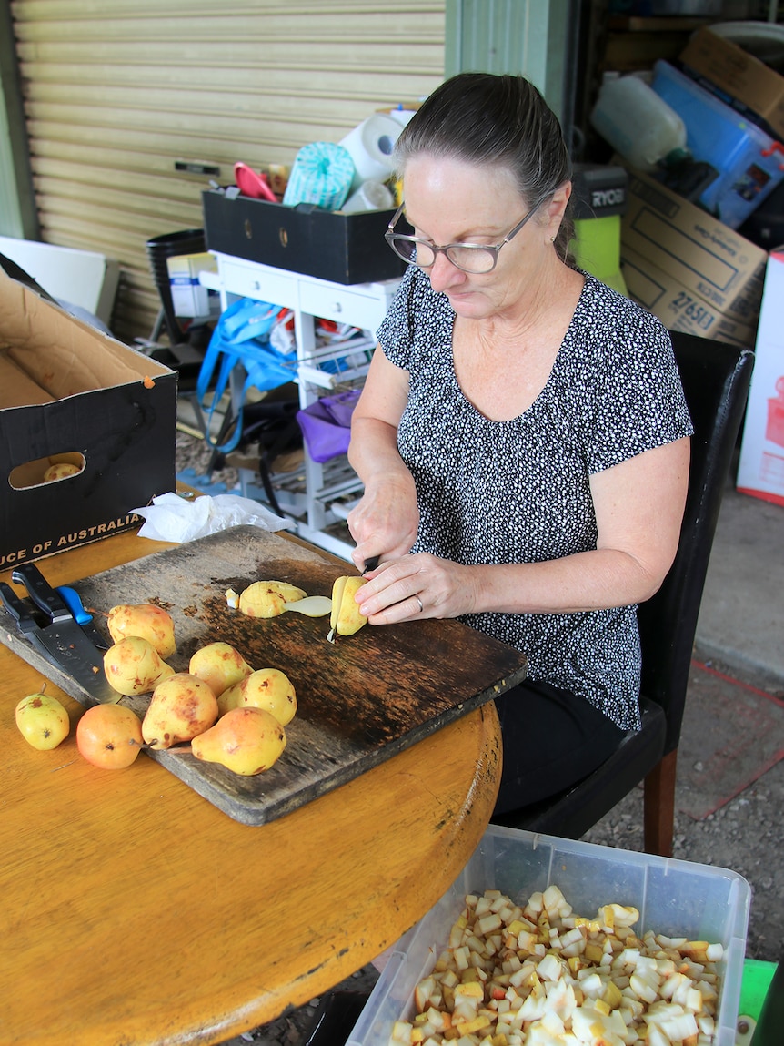 Roslyn Mueller chops pears on a chopping board and puts them into a large bucket.