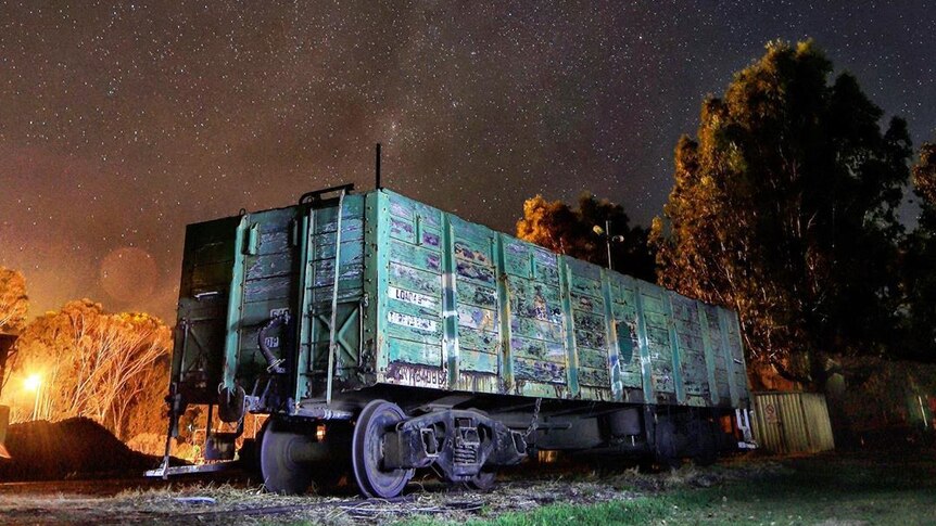 A cargo train carriage sits under a starry sky.