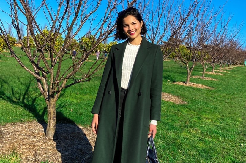 A woman in a green jacket standing outside.