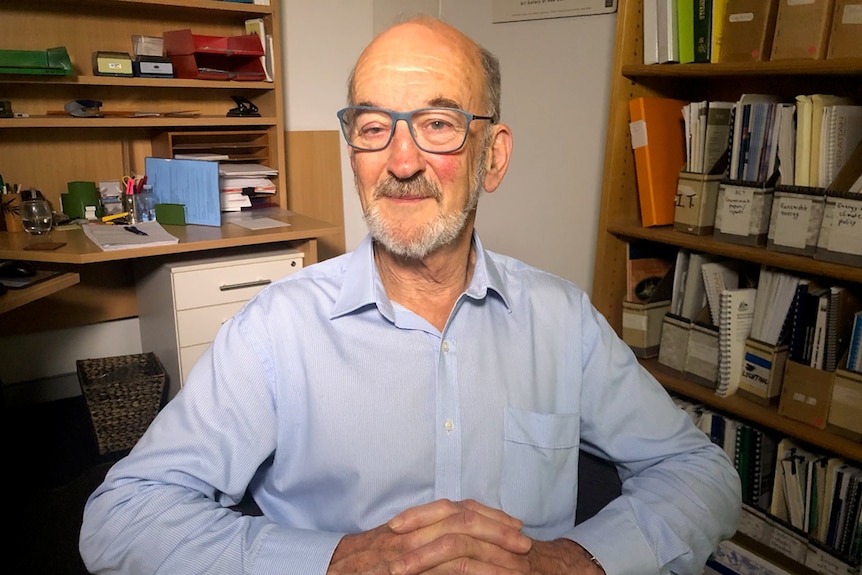 A man in an office with his hands folded.