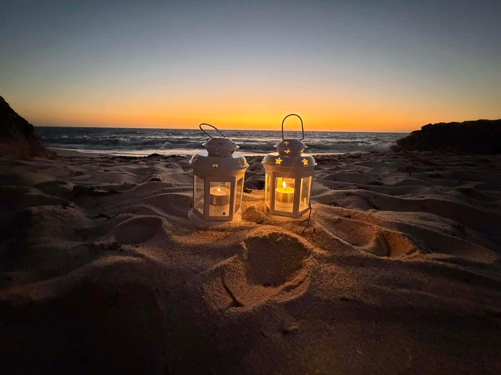 Duas luzes em lanternas numa praia. 
