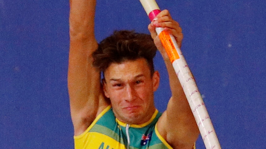 Kurtis Marschall about to vault over the bar in the pole vault. His face is contorted with the effort behind the athletic move.
