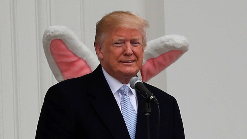 US president Donald Trump standing on the south portico of the White house with the Easter Bunny standing behind him