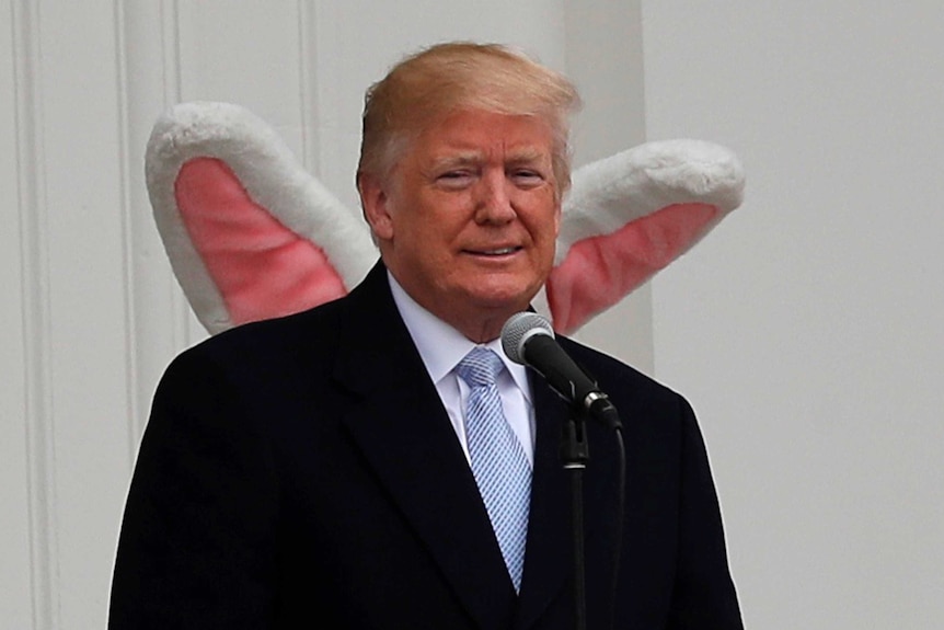 US president Donald Trump standing on the south portico of the White house with the Easter Bunny standing behind him