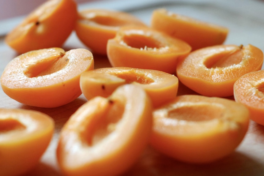 Apricot halves sit in a board.