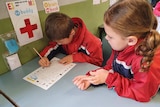 Two children writing at a desk.