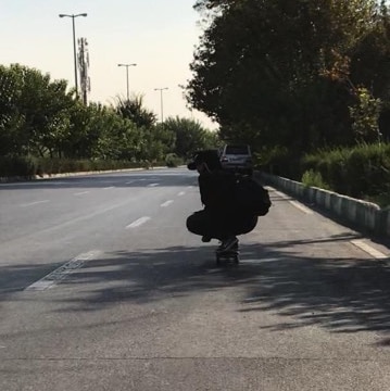 Dorsa crouching down on her skateboard in the streets of Tehran