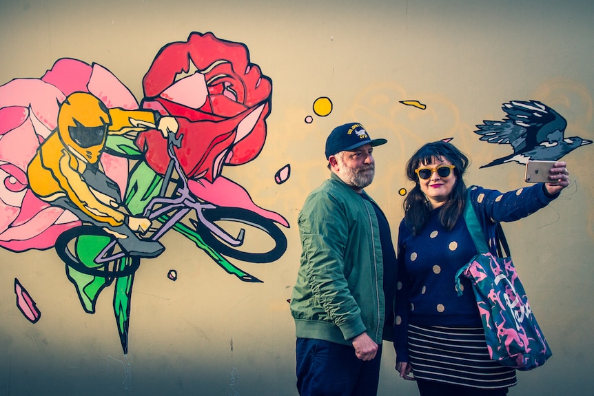 Sonny Day and Biddy Maroney in front of one of Sonny's mural works, showing creative work opportunities in regional Australia.