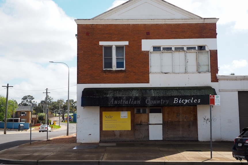 A boarded up shop with a for sale sign in the window in Griffith