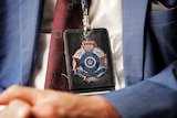 a close-up of a police badge on a lanyard being worn by a detective