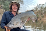 A man on a boat holding a large murray cod