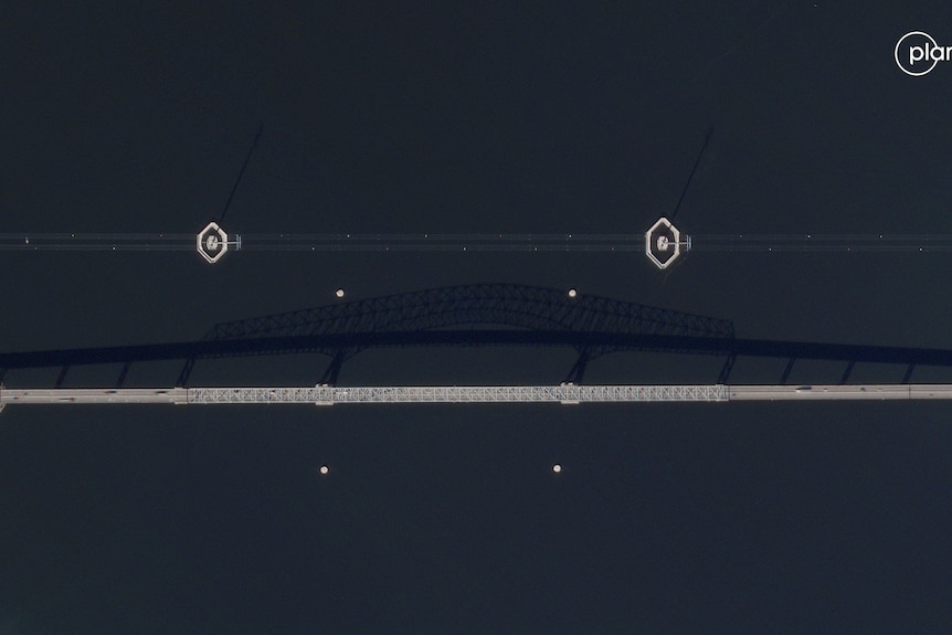 A satelite view of a long bridge with a shadow on water.