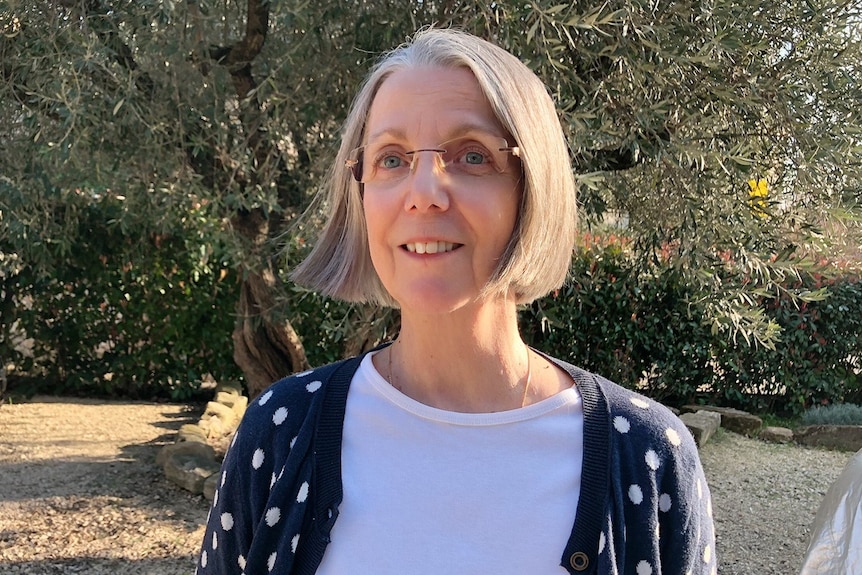 A woman standing in front of a tree.